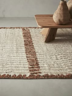 an area rug with two vases on it and a wooden bench in the background