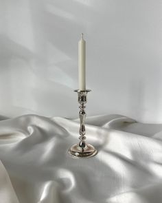 a single candle is lit on a white cloth