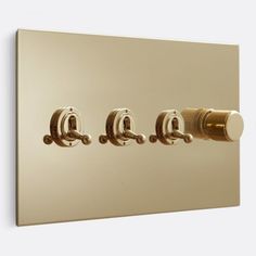 an image of three knobs on a light switch in the wall with gold trim