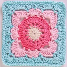 a crocheted square with a pink flower on it