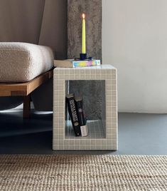 a candle is lit on top of a small box with some books and magazines in it