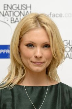 a woman with blonde hair wearing a green dress and necklace, smiling at the camera