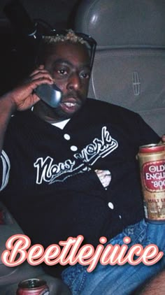 a man sitting in a car talking on a cell phone and holding a can of beer