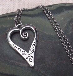 This is such a unique and whimsical heart pendant necklace.  It has incredible detail and another little heart showcased inside the main heart.  This would make a very sweet and meaningful gifts for a loved one on any occasion.  The heart measures 1” long by 5/8” wide and is made from allergy free plated silver.  It hangs from a simple 18” stainless steel necklace chain.I have matching earrings in my shop, if you would like the whole set.  Here is the link........... https://etsy.me/30EwF2x Than Silver Heart Jewelry, Brown Beaded Necklace, Whimsical Heart, Silver Heart Earrings, Beaded Pendant Necklace, Necklace Heart, Silver Heart Necklace, Charm Pendant Necklace, Feather Necklaces