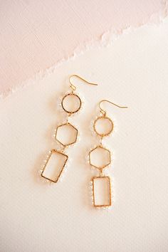 These stunning earrings boast a captivating geometric design accented with intricate beads, exuding a luxurious charm that effortlessly elevates any look. Crafted from gleaming gold-toned metal, they are both lightweight and comfortable, ensuring all-day wearability with a touch of glamour. Whether paired with casual attire or formal wear, the Caroline Geometric Dangle Earrings are the perfect choice to make a chic statement. Gold Geometric Beaded Earrings As A Gift, Gold Geometric Beaded Earrings For Gift, Gold Beaded Geometric Earrings, Gold Geometric Beaded Earrings, Geometric Beaded Gold Earrings, Geometric Gold Beaded Earrings, Chic Gold Beaded Dangle Earrings, Chic Gold Dangle Beaded Earrings, Minimalist Gold Beaded Earrings