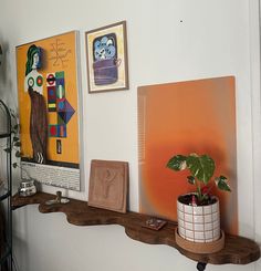 a shelf with some art on it and a potted plant in the corner next to it