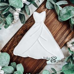 a cookie shaped like a bride's dress surrounded by greenery and white pearls