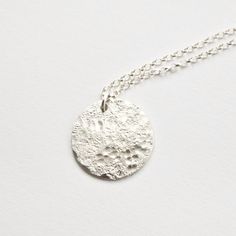 This silver moon necklace features a solid sterling silver disc that I have textured with a hammer by hand so each one will be completely unique. The texture gives a really interesting moonscape effect with a distressed stone imprint and rounded dimple pattern. It is the perfect pendant for layering with other simple jewellery for a minimal, modern look. The disc measures around 20mm diameter and the sterling silver chain comes in a choice of lengths. I textured it by hammering it on a rough sto Minimalist Hammered Coin Necklace, Minimalist Round Hammered Coin Necklace, Minimalist Hammered Round Coin Necklace, Hammered Sterling Silver Necklaces In Silver, Minimalist Hammered Round Disc Necklace, Hammered Round Disc Minimalist Necklace, Silver Moon-shaped Jewelry With Coin Pendant, Silver Hammered Round Pendant Necklace, Hammered Round Coin Necklace