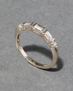 an engagement ring with three baguets on the side, sitting on a gray surface