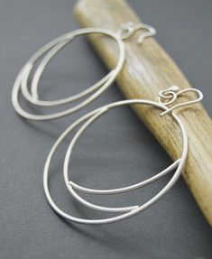 Silver hoops made from sterling silver 16 gauge wire.  These Eclipse earrings were shaped and meticulously pieced together by hand.  The hoops were tumbled for several hours to give them strength and durability, afterwards buffed to a brush finish.  One of my favorite designs!  An everyday statement earring that is unique and crafted with passion.~Length 2.25 inches~Width 2 inches~The earrings pictured are not the exact ones that you will receive, but a twin version will be duplicated with sligh Minimalist Handmade Hoop Wrap Earrings, Modern Wire Wrapped Hoop Earrings, Handmade Sterling Silver Hoop Wrap Earrings, Modern Handmade Sterling Silver Hoop Earrings, Modern Sterling Silver Wire Wrapped Hoop Earrings, Unique Hand Forged Sterling Silver Hoop Earrings, Handmade Silver Plated Hoop Earrings, Small Hoop Wire Wrapped Silver Earrings, Handmade Small Hoop Sterling Silver Wrap Earrings