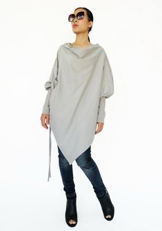 "🚚..ALL ORDERS ARE SHIPPED VIA DHL EXPRESS MAIL This batwing tunic is a very \"cool\" addition to any wardrobe! With a unique drawstrings on bottom hem of tunic provide plenty of options for changing the look. Cowl neckline, batwing sleeves with wide cuffed and oversized side pocket; can be worn layered over leggings, pants, or skirt for even more dramatic effects. * Pull-on style * Cowl neckline * Dropped shoulders * Long sleeves with wide ribbed cuff * Oversize side pocket * Asymmetrical hem Oversized Tops With Asymmetrical Hem For Fall, Asymmetrical Gray Top For Fall, Oversized Winter Top With Asymmetrical Hem, Asymmetrical Cotton Tops For Fall, Oversized Cotton Tunic For Fall, Oversized Asymmetrical Spring Sweater, Oversized Asymmetrical Sweater For Spring, Oversized Asymmetrical Winter Tops, Gray Long-sleeved Poncho For Layering