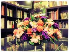 a vase filled with flowers sitting on top of a table in front of a book shelf