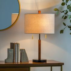 a lamp sitting on top of a wooden table next to a mirror and bookend