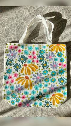 a colorful flowered bag sitting on top of a white table next to a gray blanket