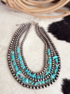 Handmade 5-strand Chip Stone & Navajo Bead Necklace | Gussied Up Online Boutique Indulge in the western style with our polished silver beaded necklace adorned with vibrant turquoise colored stones. Our five stranded layered necklace adds a touch of elegance to any outfit. Upgrade your jewelry game with our tiered necklace and make a statement wherever you go! 24" Long, Handmade 5-strand Chip Stone & Navajo Bead Necklace * 5-strand (20", 22", 22", 24", 24" long) necklace & 5" extender * 20" long, Southwestern Multi-strand Turquoise Beaded Necklace, Southwestern Multi-strand Turquoise Gemstone Necklace, Southwestern Multi-strand Turquoise Necklace For Jewelry Making, Pearls Fashion, Silver Beaded Necklace, Outfit Upgrade, Western Necklaces, Tiered Necklace, Western Accessories