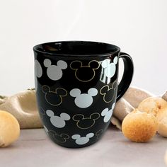 a mickey mouse mug sitting on top of a table next to rolls and some bread