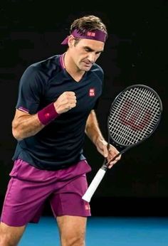 a man holding a tennis racquet on top of a tennis court with his fist in the air