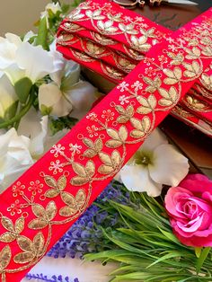 two red and gold ribbons with flowers in the foreground, one on top of each other