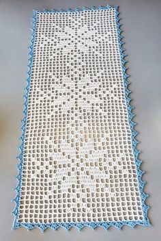 a crocheted table runner with blue trim