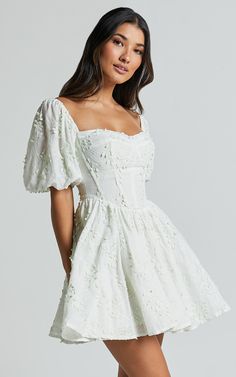 Celebrate the beauty of spring with our Esthela Mini Dress in Pale Mint. This enchanting piece features an embroidered square neck and short puff sleeves, giving it a sweet and feminine look. The corset detail cinches your waist for a flattering fit, while the flowy fit-and-flare silhouette adds a touch of romance to your outfit. Made from soft cotton fabric, this dress is perfect for both day-time parties and special occasions. Embrace your unique style and feel empowered in this gorgeous mini White Grad Dresses, Winter Formal Dresses Short, White Dress Flowy, Ivory Outfit, Grad Dresses Short, White Dresses Graduation, Cotton Dress Fabric, Cute Formal Dresses, Dresses For The Races