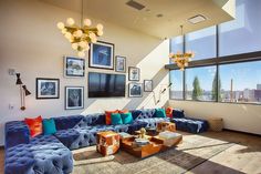 a living room filled with blue couches and pictures hanging on the wall above them