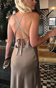 a woman standing in front of a counter wearing a dress and holding a cell phone