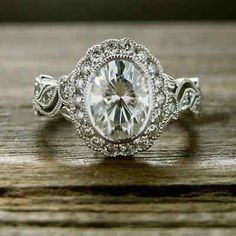 a close up view of a diamond ring on a wooden surface with the center stone surrounded by diamonds