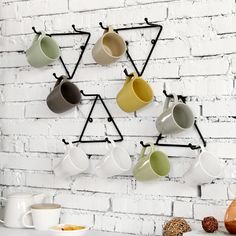 coffee cups are hanging on the wall next to a mug rack