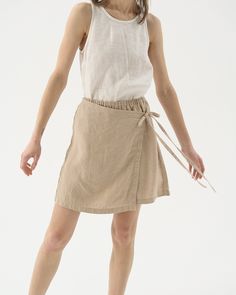 "Our take on a leisure tennis skirt - linen shorts with a wrap front, also known as a skort. The perfect blend of grace and comfort. Offered in medium-weight and exclusive linen. STYLE DETAILS * Regular fit * High rise * Elasticated waist * Wrap ties at the front * Mini length * Made from medium weight and exclusive linen SIZES & COLORS IN THE PICTURES * Model is wearing size M in Beige (medium) linen Model's height - 175 cm (5'9\"), bust 80 cm (31.5\"), waist 59 cm (23.2\"), hips 89 cm (35\"). Beige Skort For Spring, Summer Cotton Skort (shorts Skirt), Short Cotton Skirt For Summer, Summer Cotton Skort With Built-in Shorts, Cotton Mini Skirt For Summer, Short Cotton Summer Skirt, Summer Skirt-style Shorts With Elastic Waistband, Summer Skirt With Drawstring, Chic Drawstring Mini Skirt For Summer