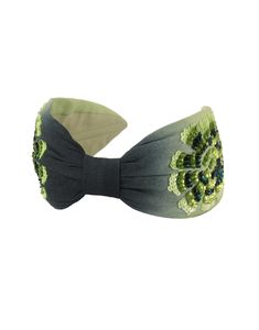 a headband with green flowers and leaves on the side, in front of a white background