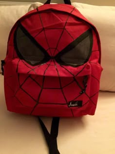 a spiderman backpack sitting on top of a bed