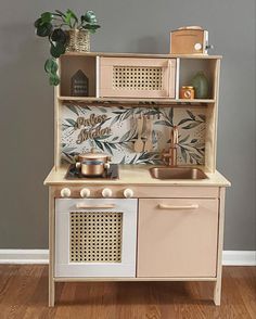 a wooden play kitchen with an oven, sink and pot holder on the top shelf