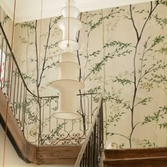 the stairs are decorated with wallpaper and decorative lighting fixtures, along with a chandelier