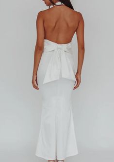 the back of a woman wearing a white dress with a large bow on it's neck