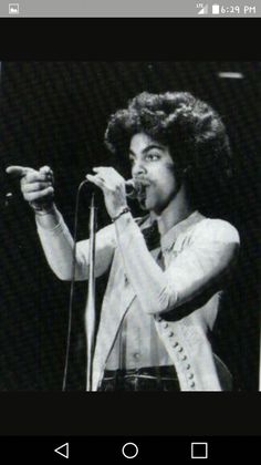 a man with an afro singing into a microphone and holding his hand out to the side