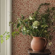 a potted plant sitting on top of a wooden table next to a wallpaper