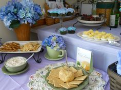 a table topped with plates and bowls filled with food next to blue hydranges