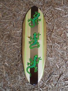 a surfboard with lizards painted on it laying in the straw next to some dry grass