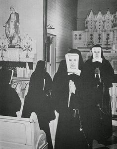 black and white photograph of three women in nun costumes with masks on their heads, standing in front of an altar