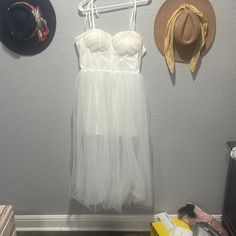 a white dress and hat hanging on a wall