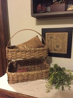 a basket sitting on top of a table next to a potted plant and framed pictures