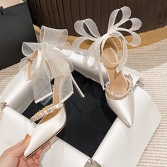 a pair of white high heeled shoes sitting on top of a table