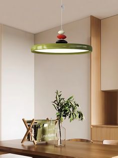 a dining room table with a potted plant in the center and hanging lights above it