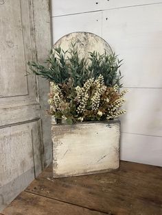 a wooden box with some plants in it on a table next to a wall and door