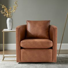 a brown leather chair sitting in front of a white vase