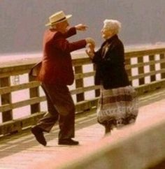 an older man and woman dancing on a pier