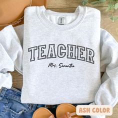 a sweatshirt with the words teacher on it next to some shoes and purses,