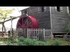 a red water wheel sitting next to a wooden house