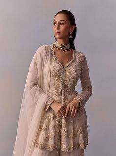 Dazzle in the elegance of the Mariam gharara set, featuring a regal ethnic design adorned with intricate hand embroidery on the jacket, enhanced with beads and sequins. Paired with a layered sharara and a coordinated dupatta, this ensemble creates a stylish look perfect for festive celebrations and wedding occasions. Traditional Long Sleeve Sharara With Sheer Dupatta, Traditional Sharara With Sheer Dupatta, Cream Sharara With Straight Kurta And Dupatta, Traditional Beige Sharara With Straight Kurta, Cream Floor-length Sharara With Dupatta, Cream Palazzo Set With Dupatta For Festivals, Traditional Beige Designer Sharara, Beige Straight Kurta Sharara For Diwali, Semi-stitched Cream Anarkali Sharara