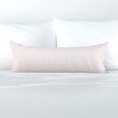 a bed with white sheets and pink striped pillows